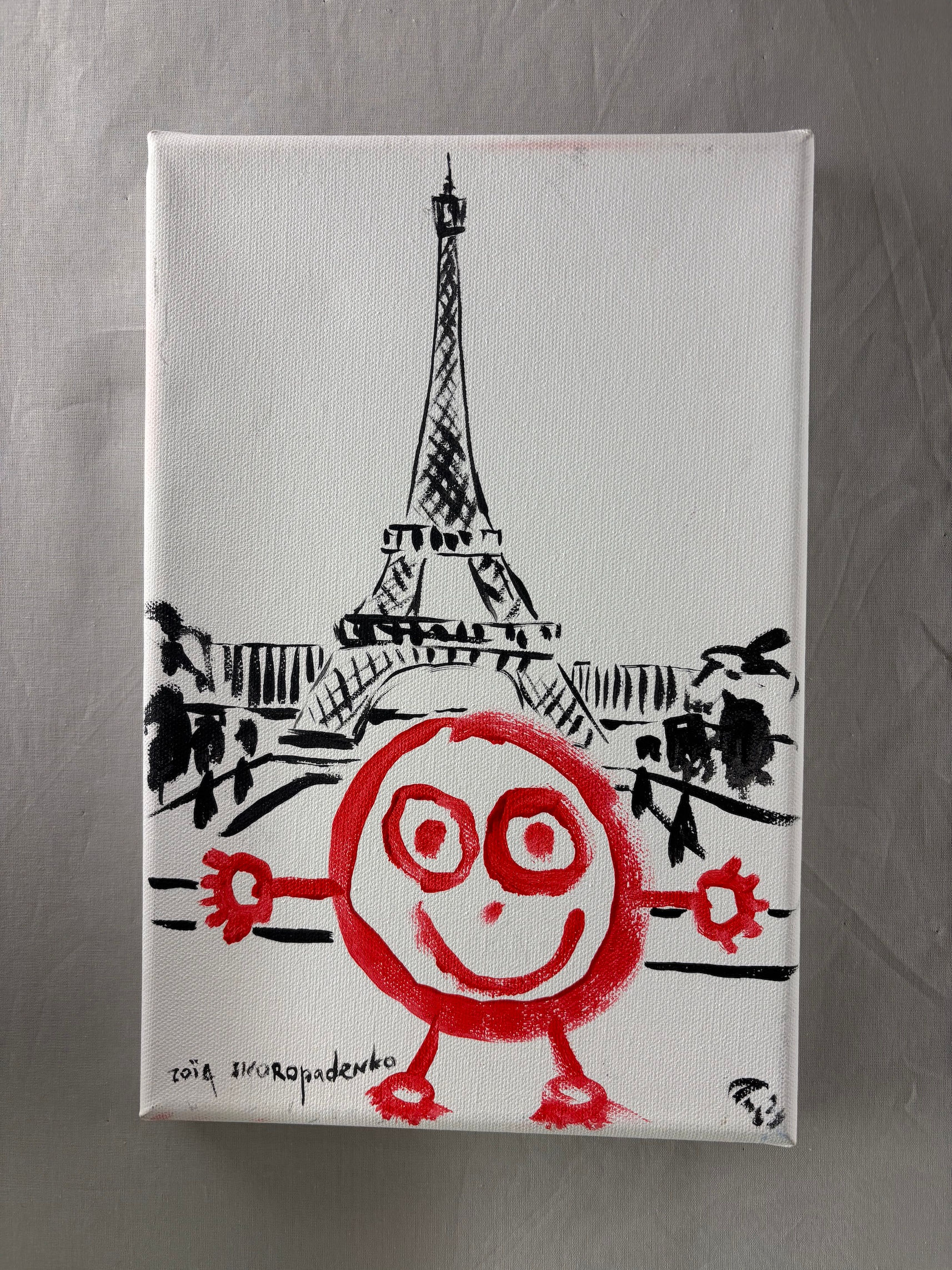 Original painting of a red round smiling figure with arms outstretched in front of a black ink Eiffel Tower, signed Zoia Skoropadenko at lower left